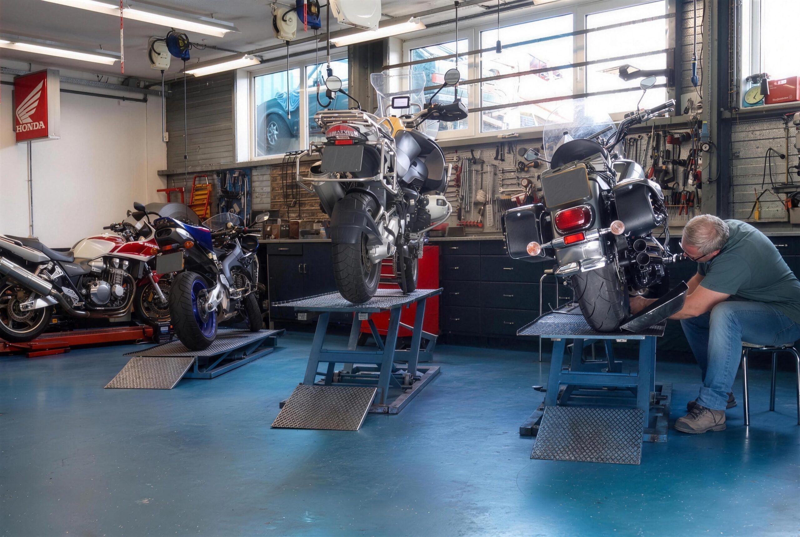 De werkplaats van Bakker Motors: drie hefbruggen, monteur aan het werk