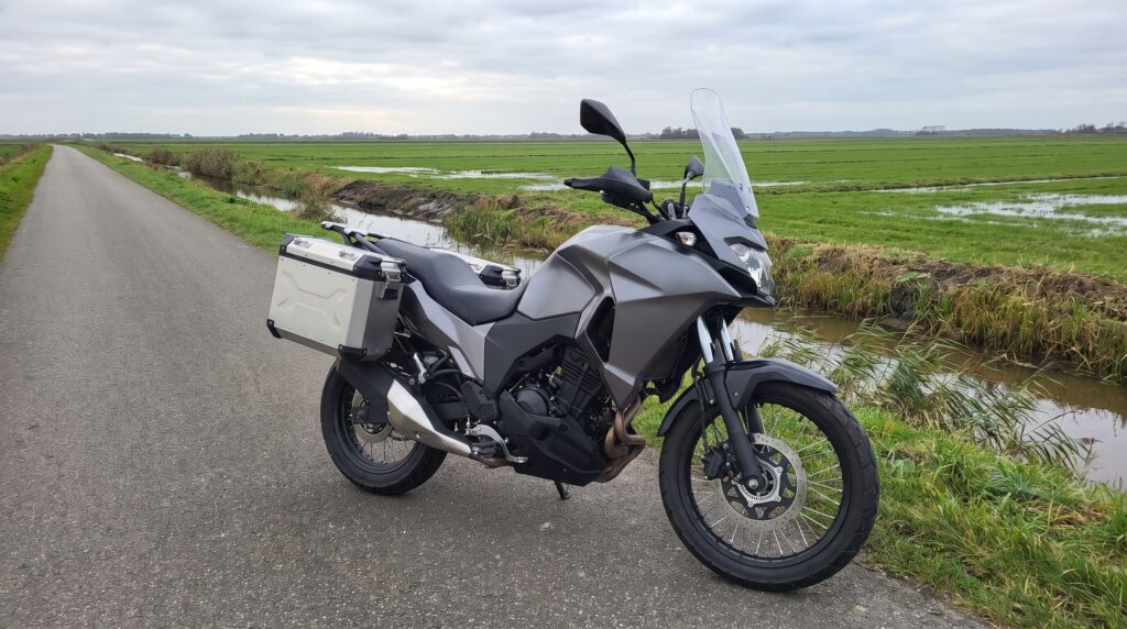 Adventure-touring motor met koffers op een rustige dijkweg langs een sloot in de polder
