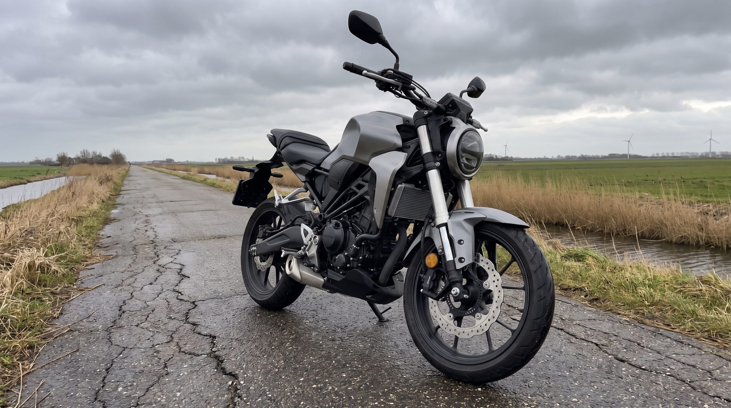 Naked motor met telescopische voorvork op een natte dijkweg in de polder